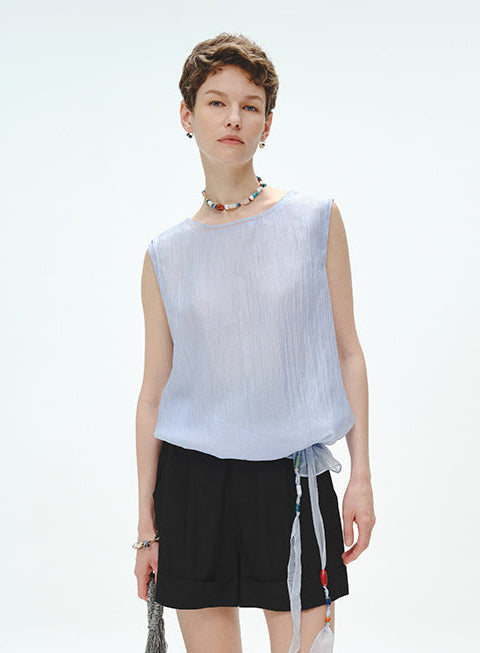 Woman wearing a light blue sleeveless top and black skirt with a white background
